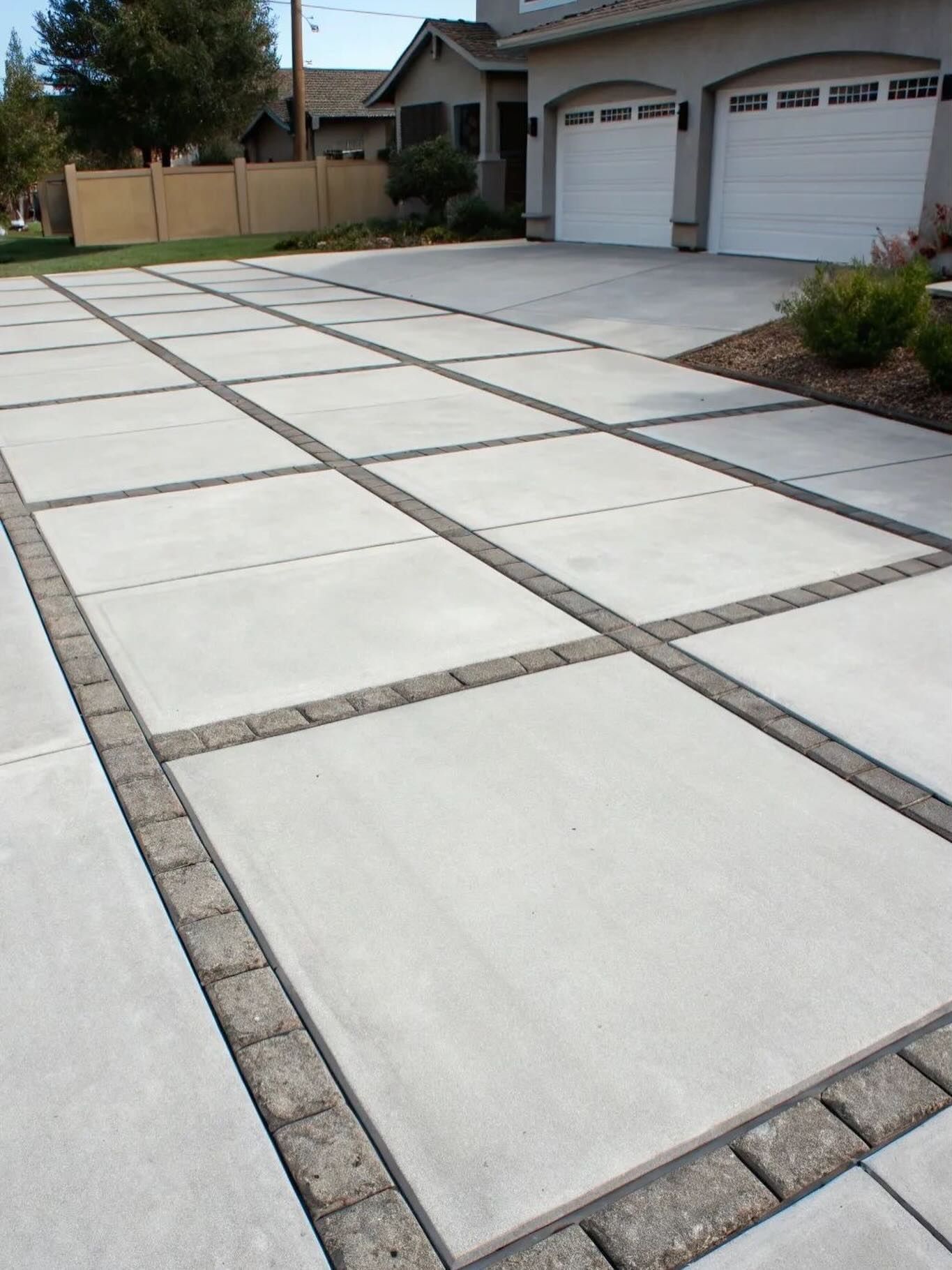 Concrete driveway with large square slabs and a two-car garage in front of a house