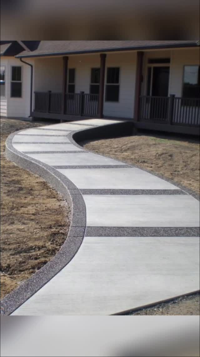 Curving concrete walkway leading to a building with covered porch and black railings