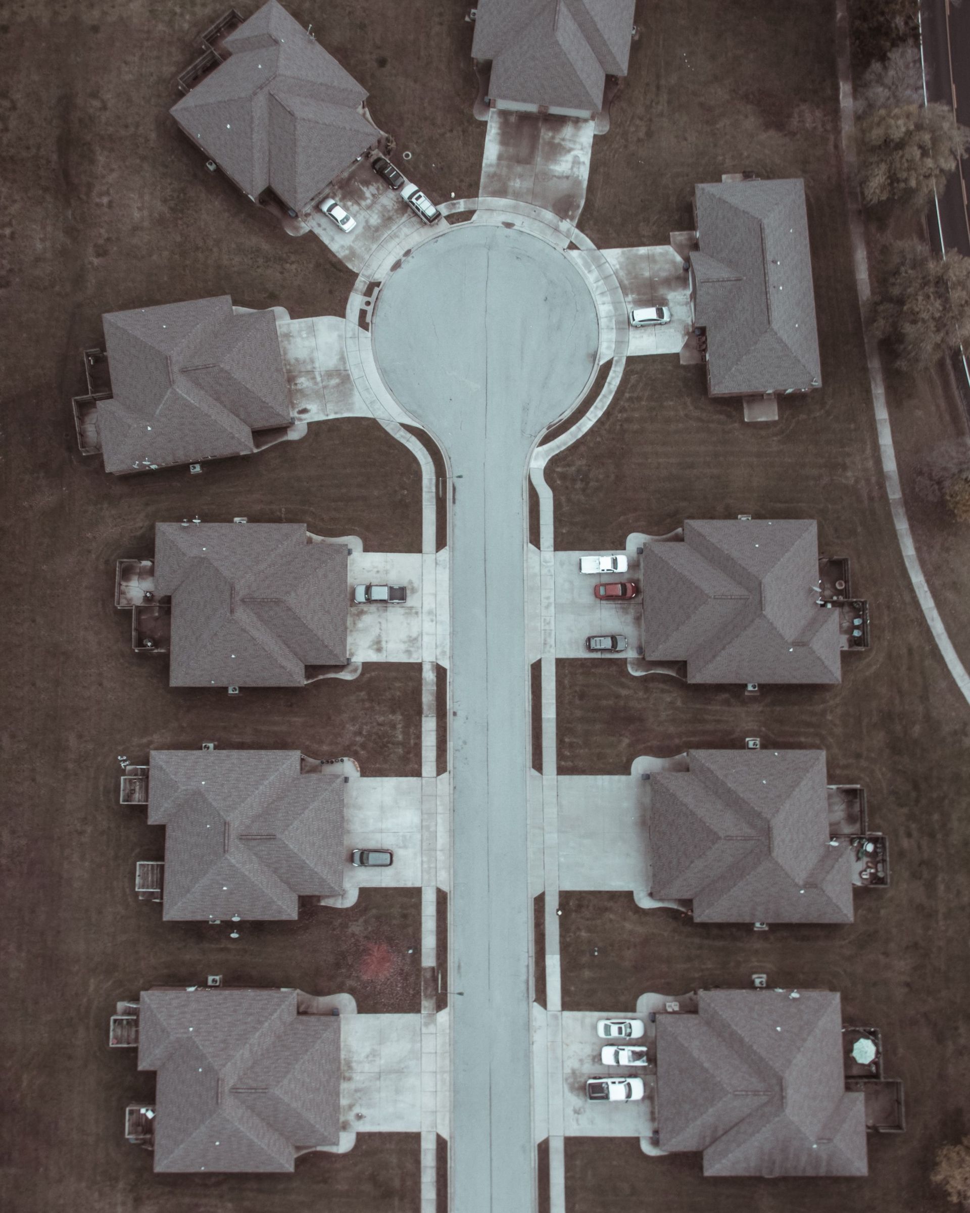 Aerial view of a cul-de-sac with six houses around a circular road and a straight street below.