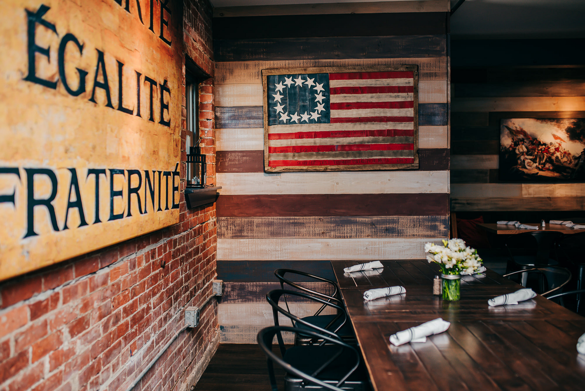 Rustic cafe interior with patriotic wall art, brick walls, and a wooden table with flowers