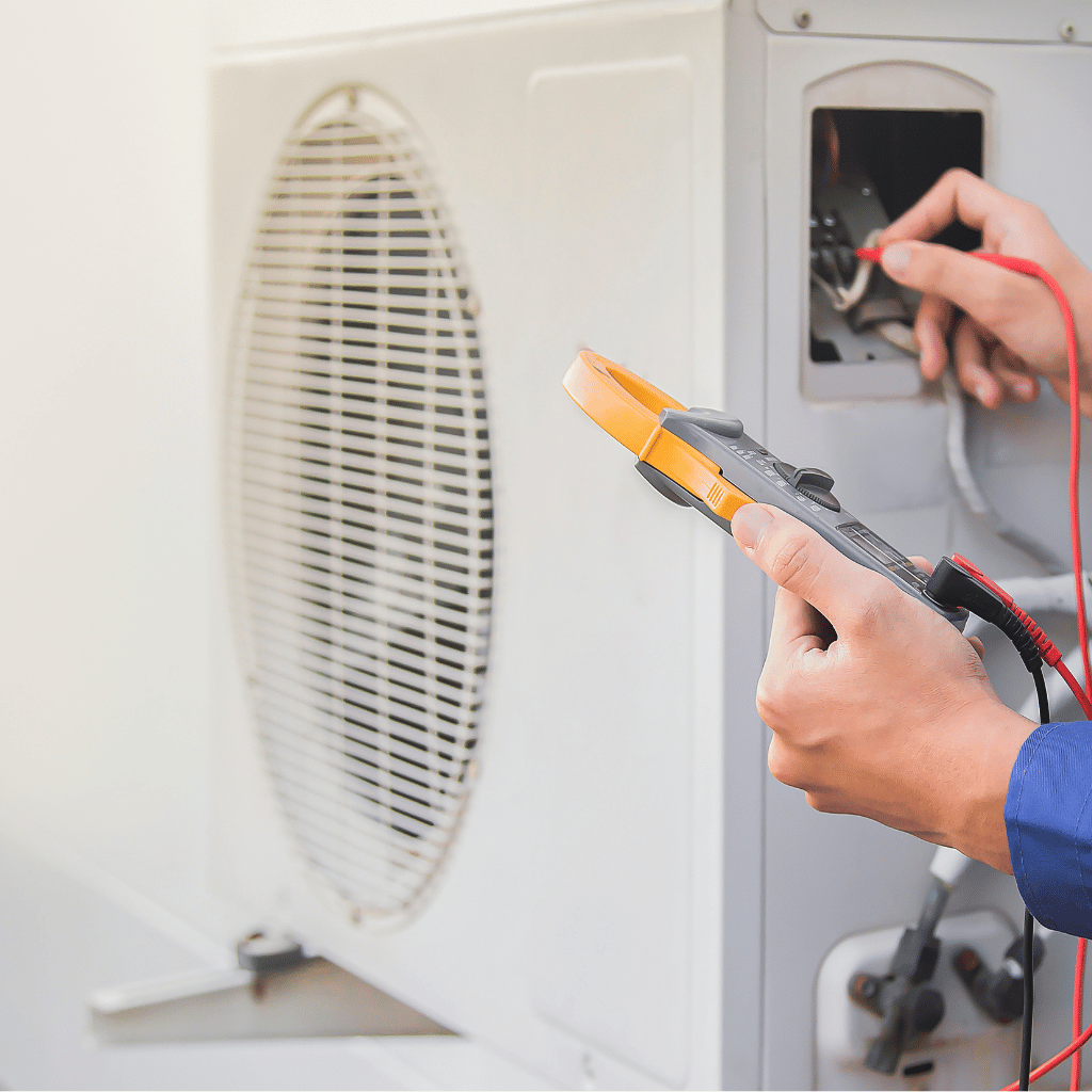 Technician using a multimeter to inspect an air conditioning unit.