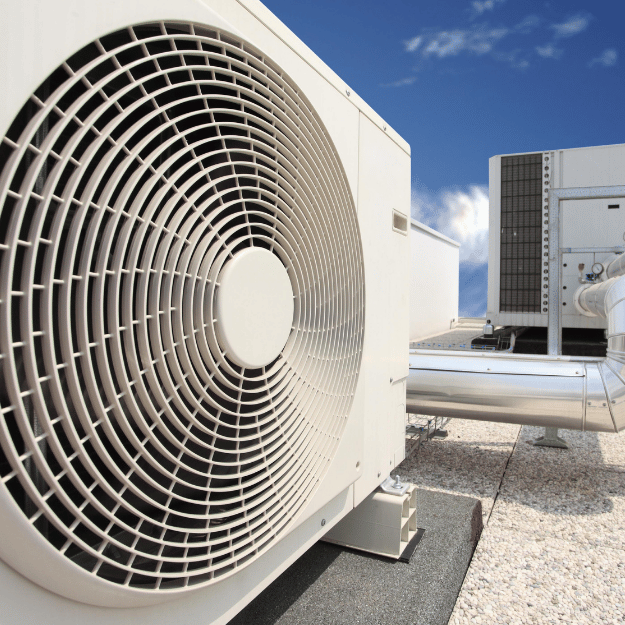 Air conditioning units on a rooftop against a blue sky.