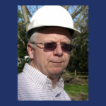 Man wearing sunglasses and a white hard hat.