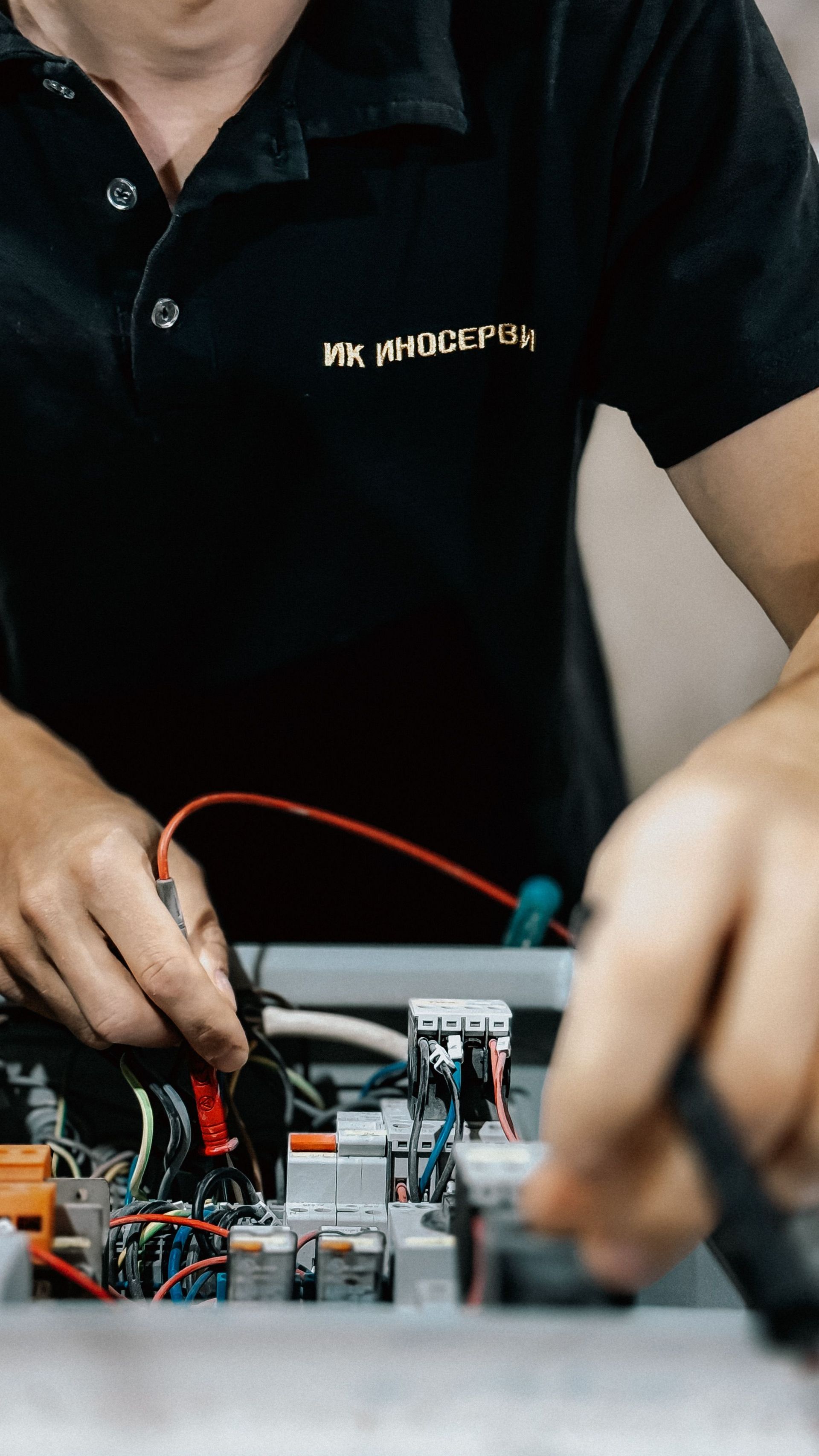 Person in a black shirt working with electronic components and wires on a circuit board.