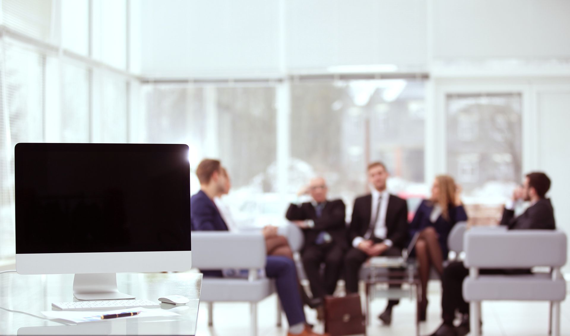 A group of business people are sitting around a table in an office.
