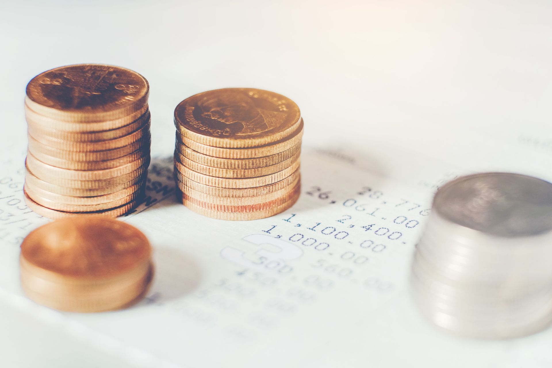 Three stacks of coins are sitting on top of a receipt.