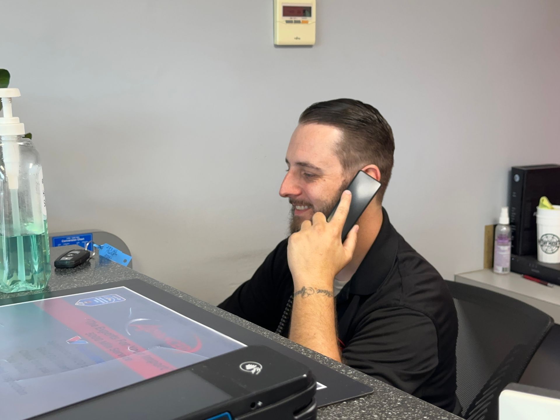 Man on a phone at a desk with a large touchscreen monitor in an office | Advanced Car Care Center LLC