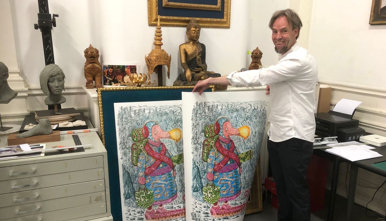 Een man staat naast twee kleurrijke abstracte schilderijen in een kamer vol kunst.