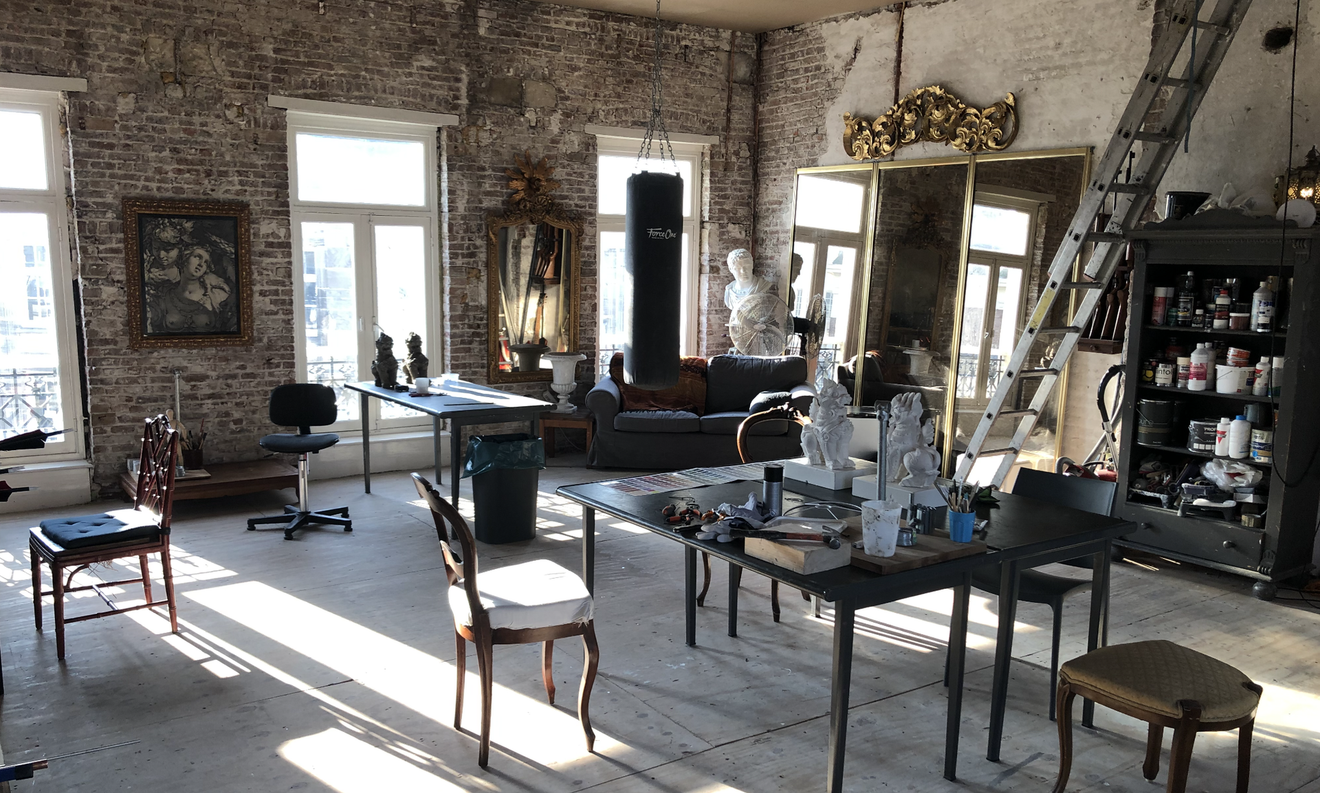 Zonnig loftinterieur met stoelen, tafels, spiegels en rustieke bakstenen muren.