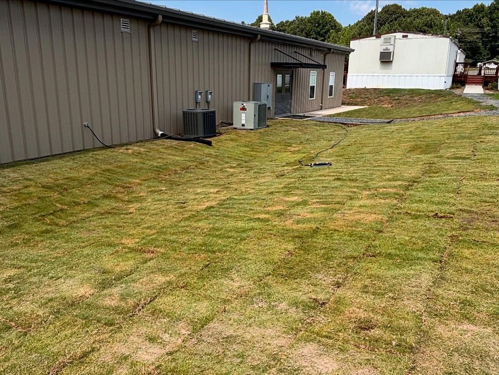 Exterior view of a building with brown siding and patches of green grass in the yard.