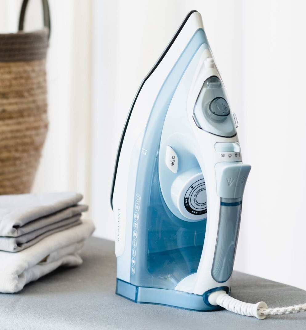 A blue and white iron is sitting on an ironing board