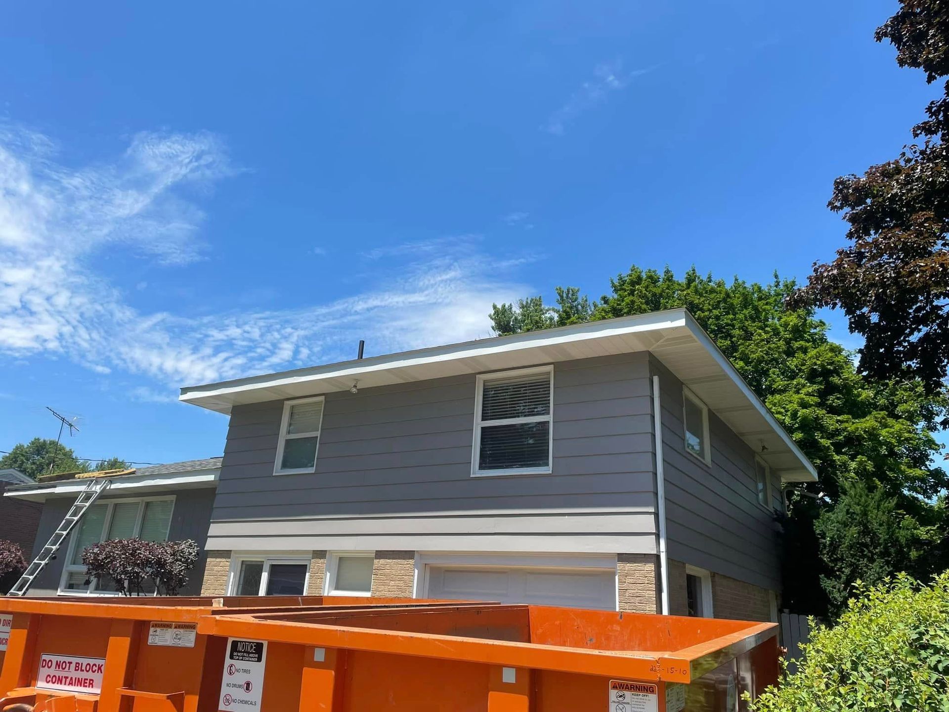 A house with a large orange dumpster in front of it