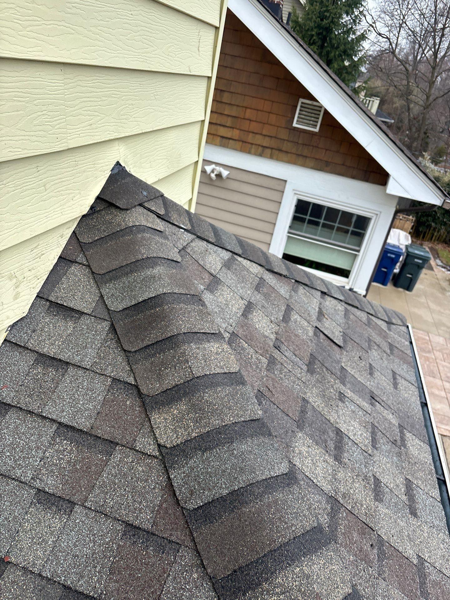 A close up of a roof with shingles on it next to a house.