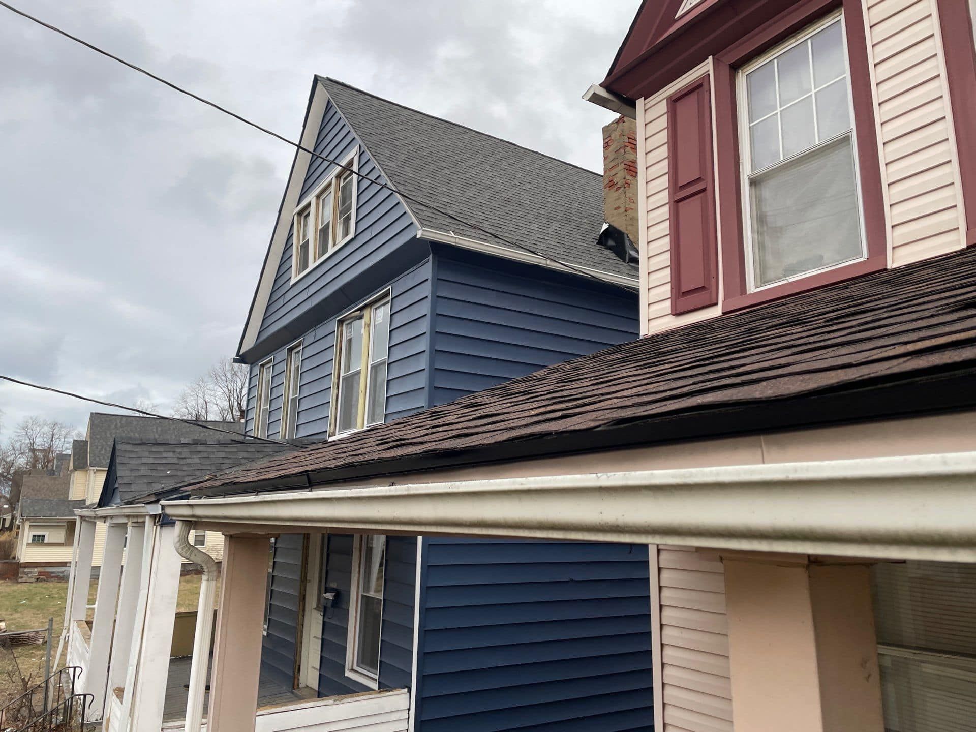 A blue house with a red trim is next to a red and white house.