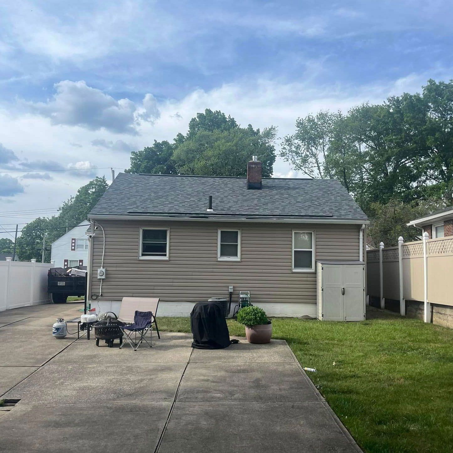 The backyard of a house with a grill and chairs