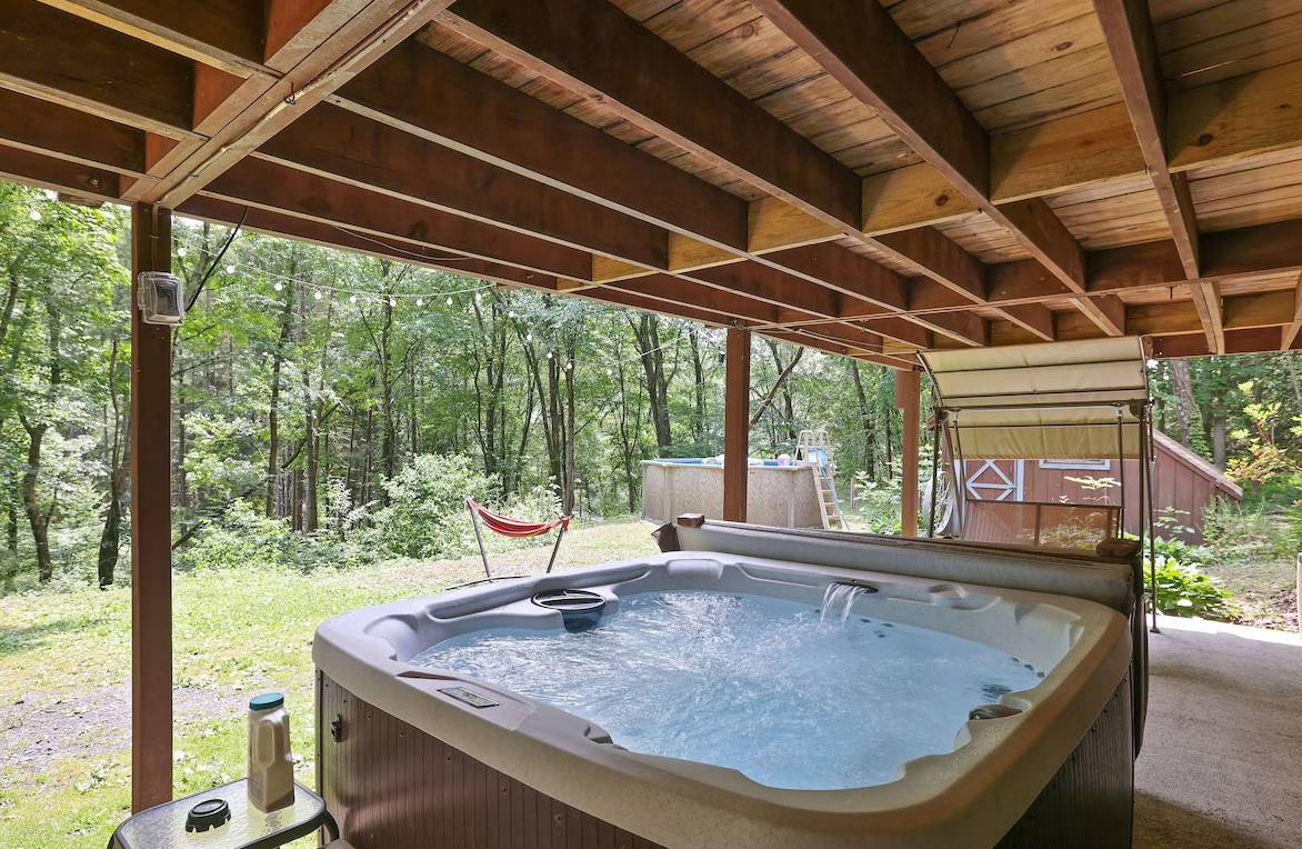A hot tub is under a wooden deck in the woods.