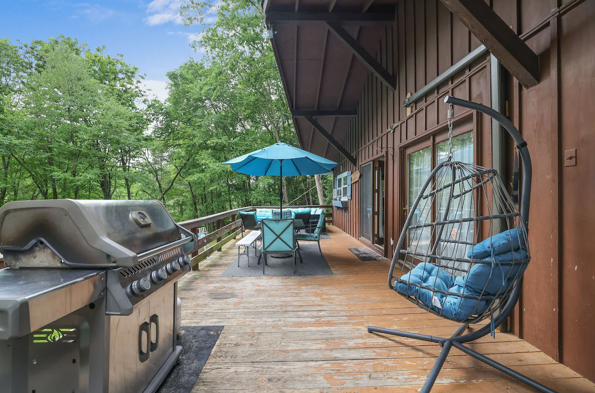 There is a grill and a swing on the deck.