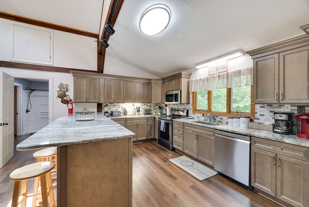 A kitchen with wooden cabinets , stainless steel appliances , and a large island.