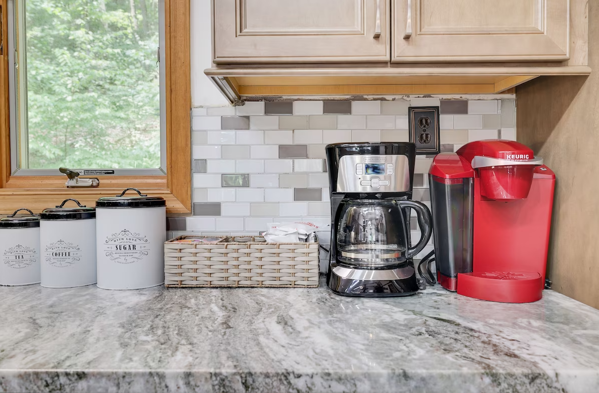 A kitchen counter with a coffee maker and a kettle on it.