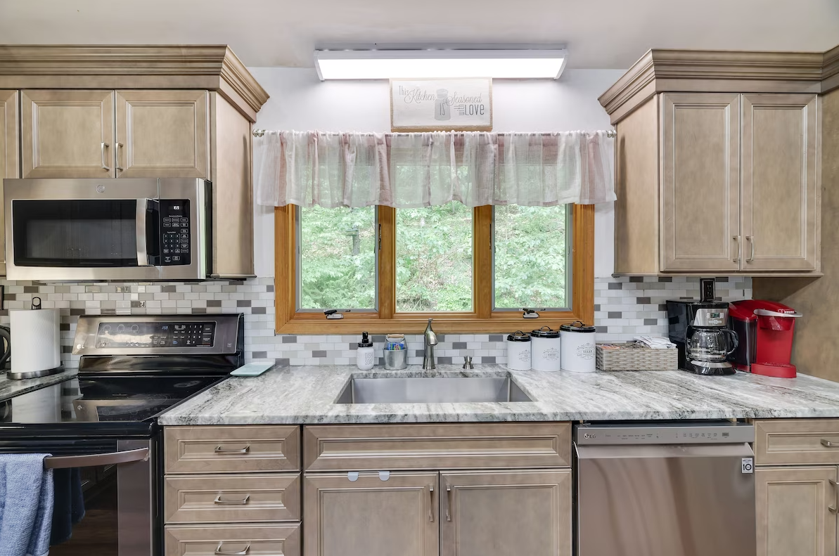 A kitchen with a sink , stove , microwave , and dishwasher.