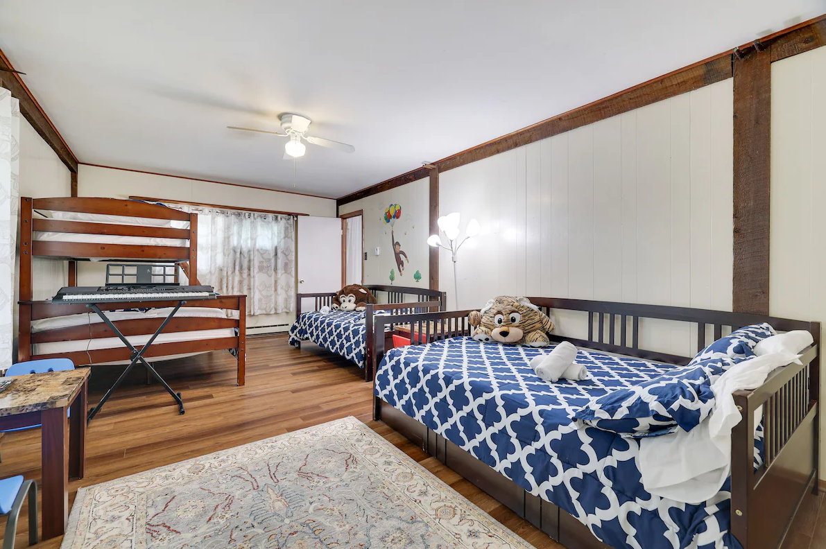 A bedroom with two beds , a bunk bed and a piano.
