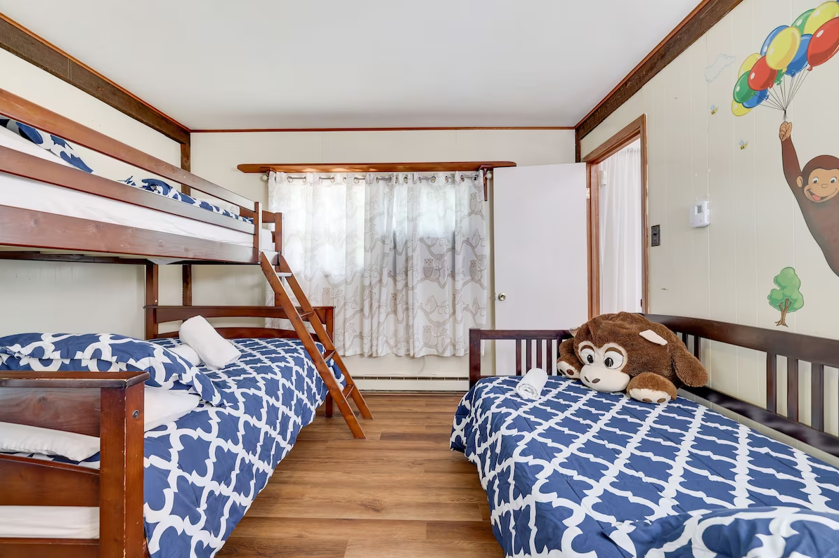A bedroom with three bunk beds and a monkey on the wall.