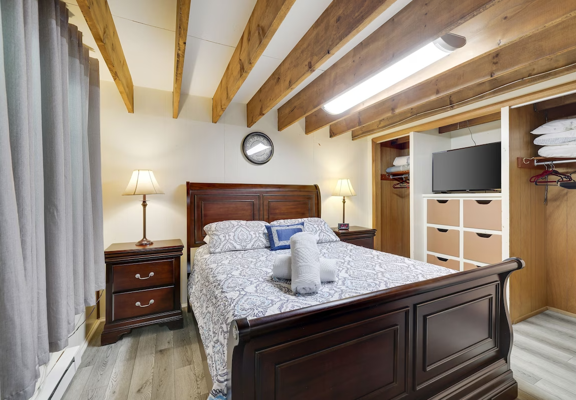 A bedroom with a bed , nightstand , television and closet.