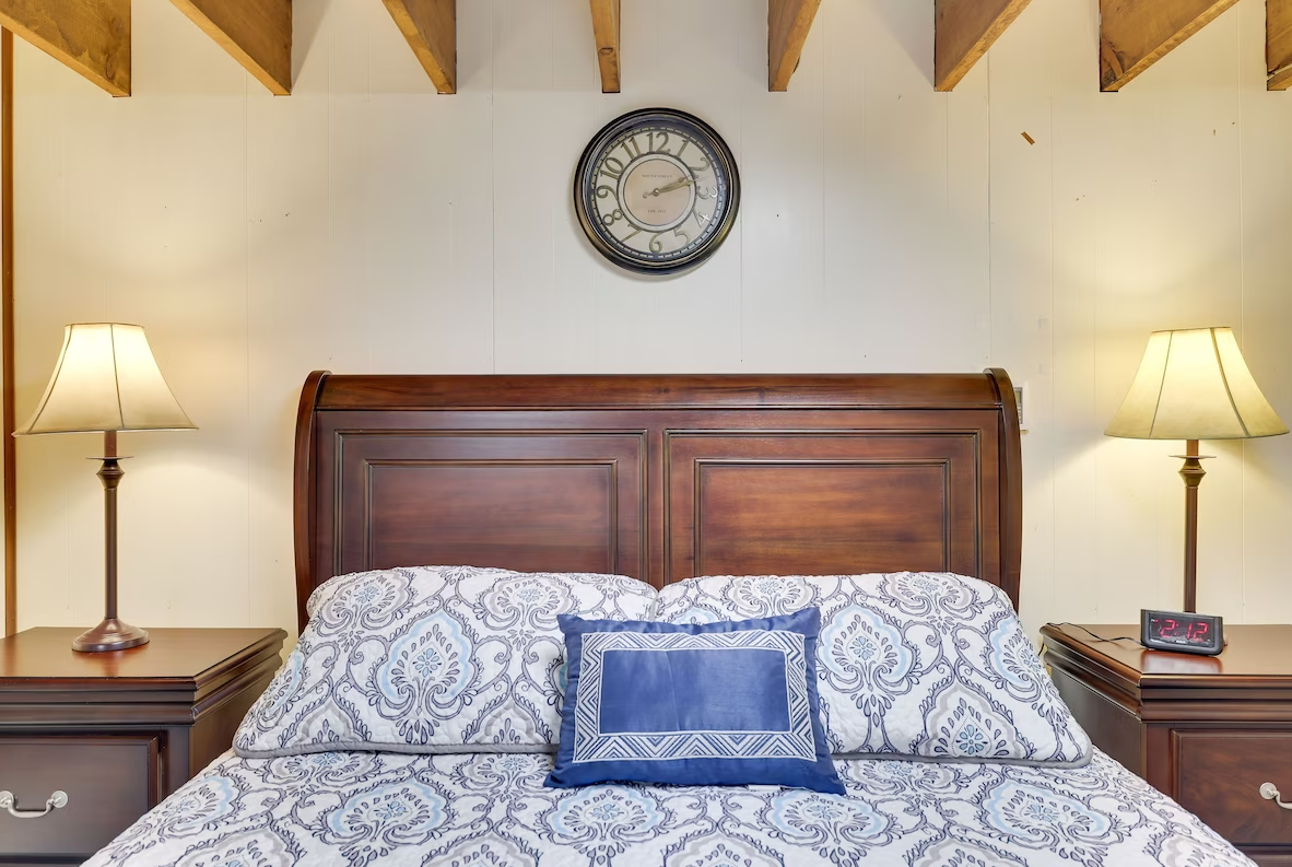 A bedroom with a clock on the wall above the bed