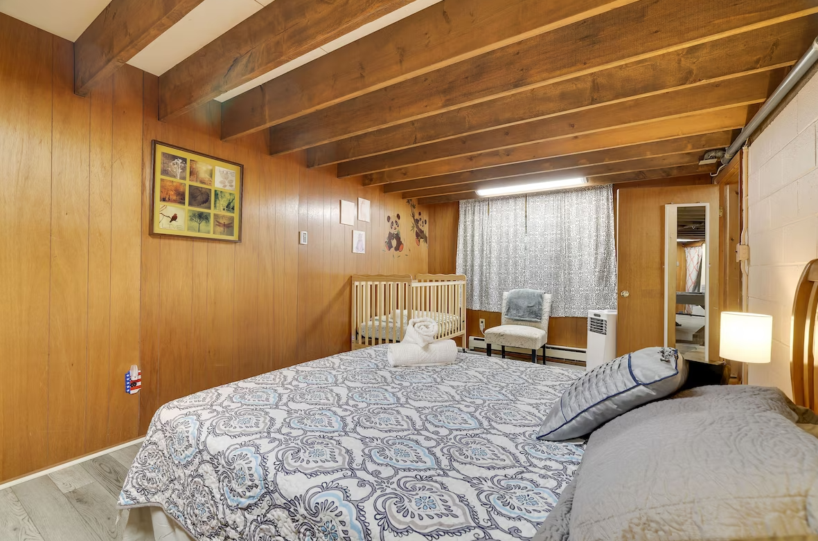 A bedroom with a large bed and a wooden ceiling.