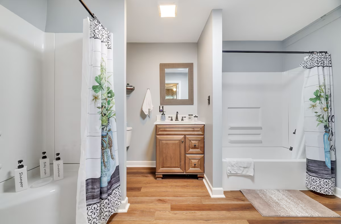 A bathroom with a sink , tub , mirror and shower curtain