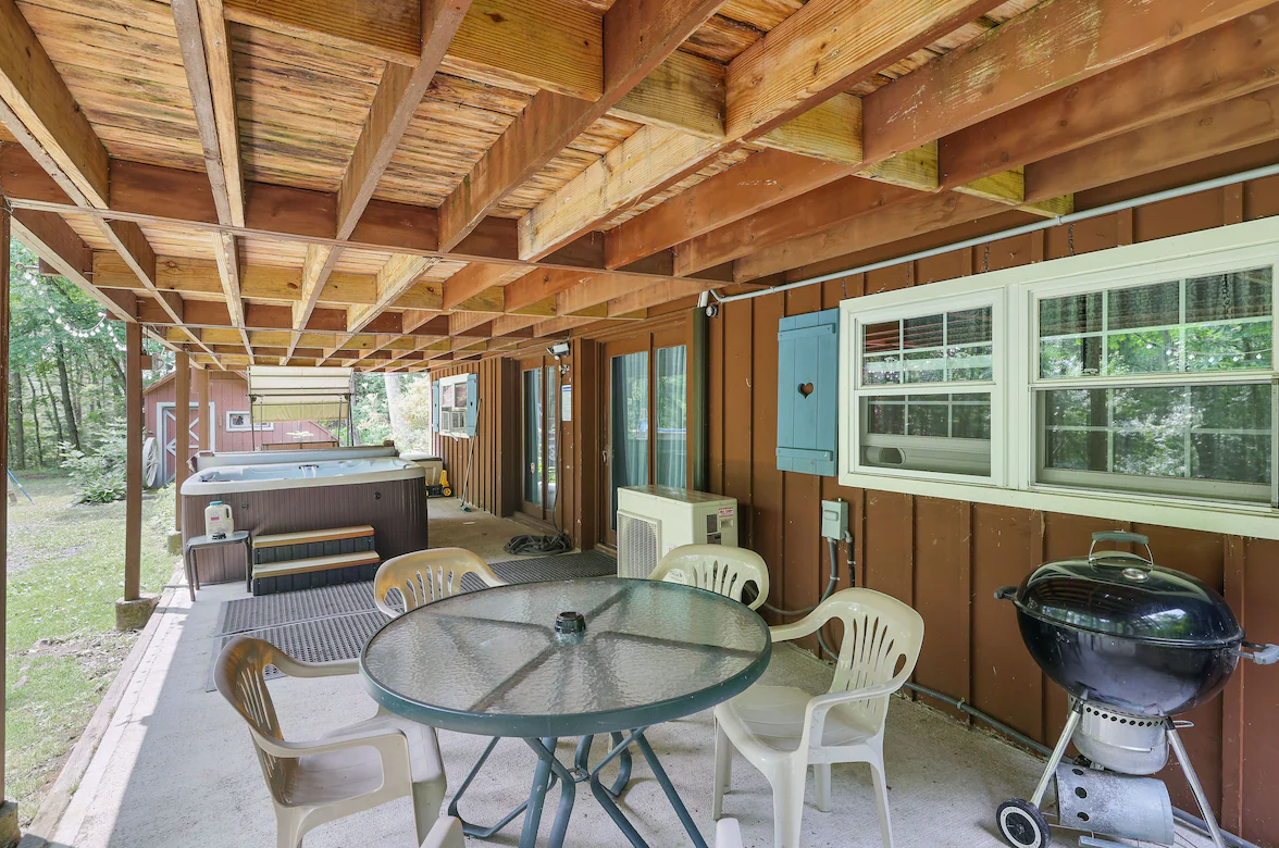 There is a table and chairs on the porch of a house.