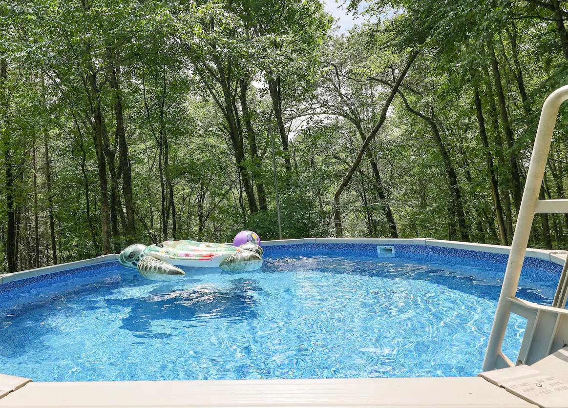 A swimming pool with a raft in it and trees in the background.