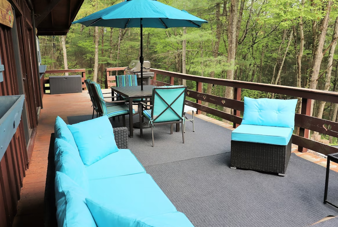 A deck with a couch , chairs , table and umbrella.