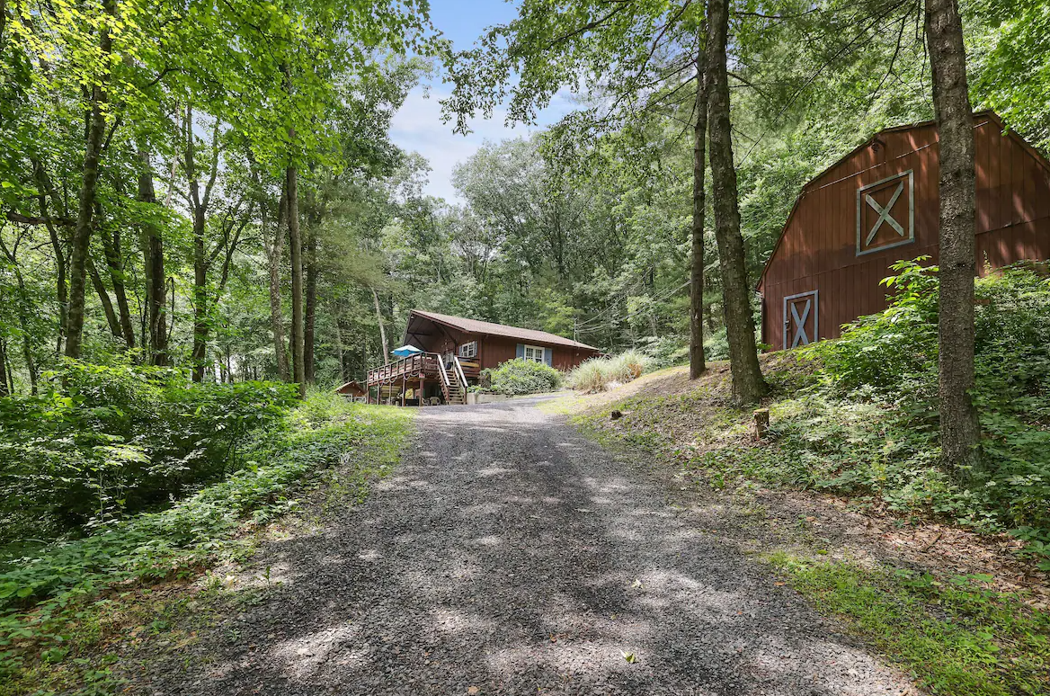 A dirt road leading to a barn in the woods.
