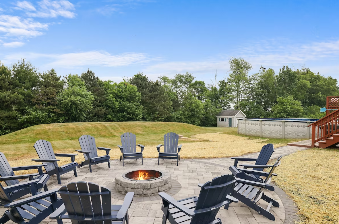 A group of chairs are sitting around a fire pit on a patio.