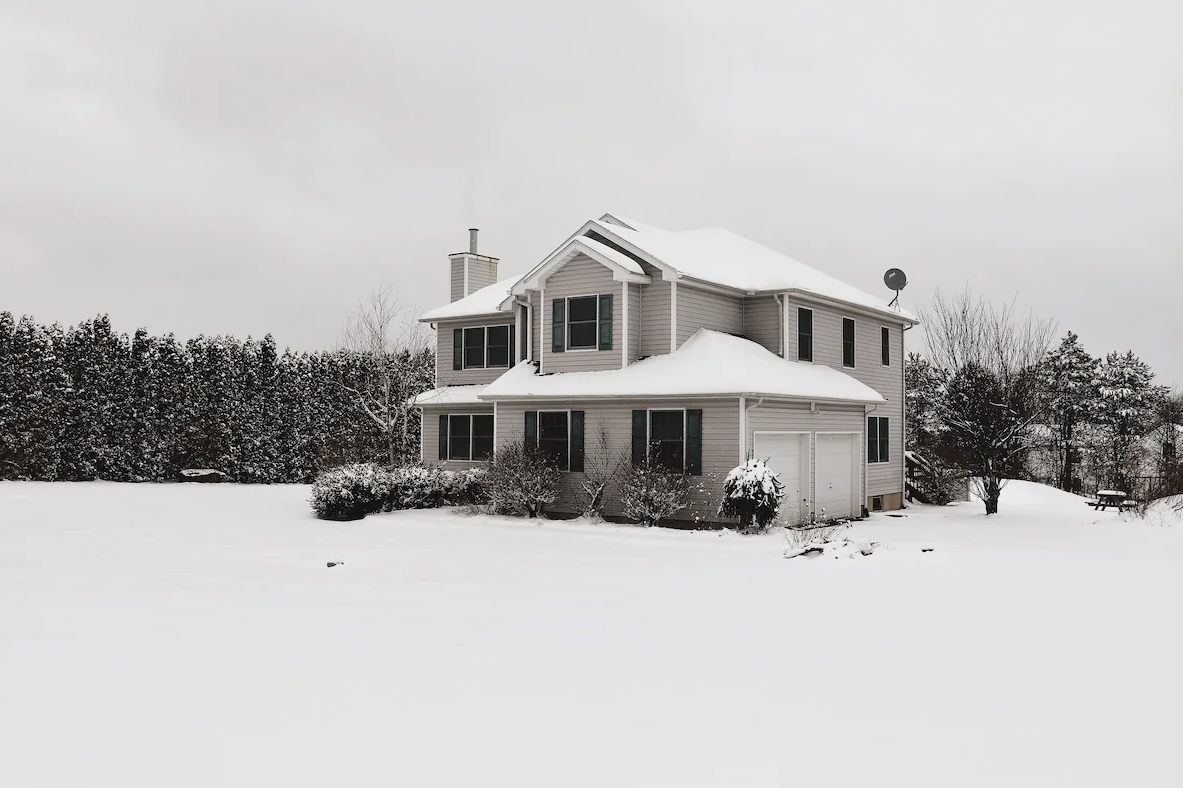 A black and white photo of a house covered in snow.