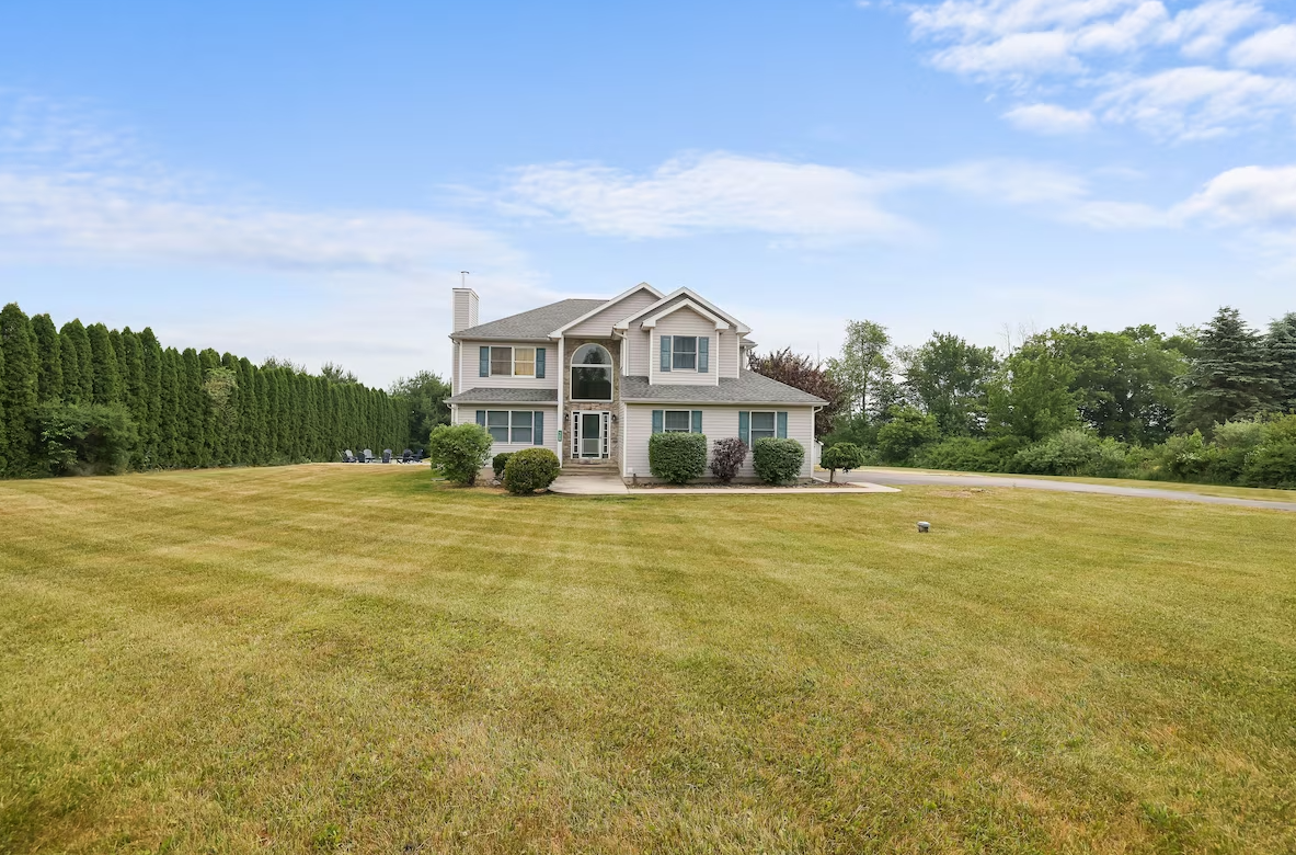 A large house is sitting on top of a lush green field.