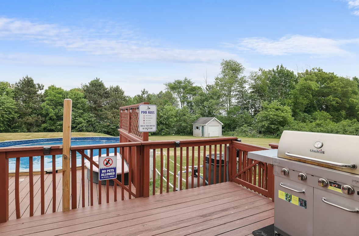 A grill is on a deck next to a pool.