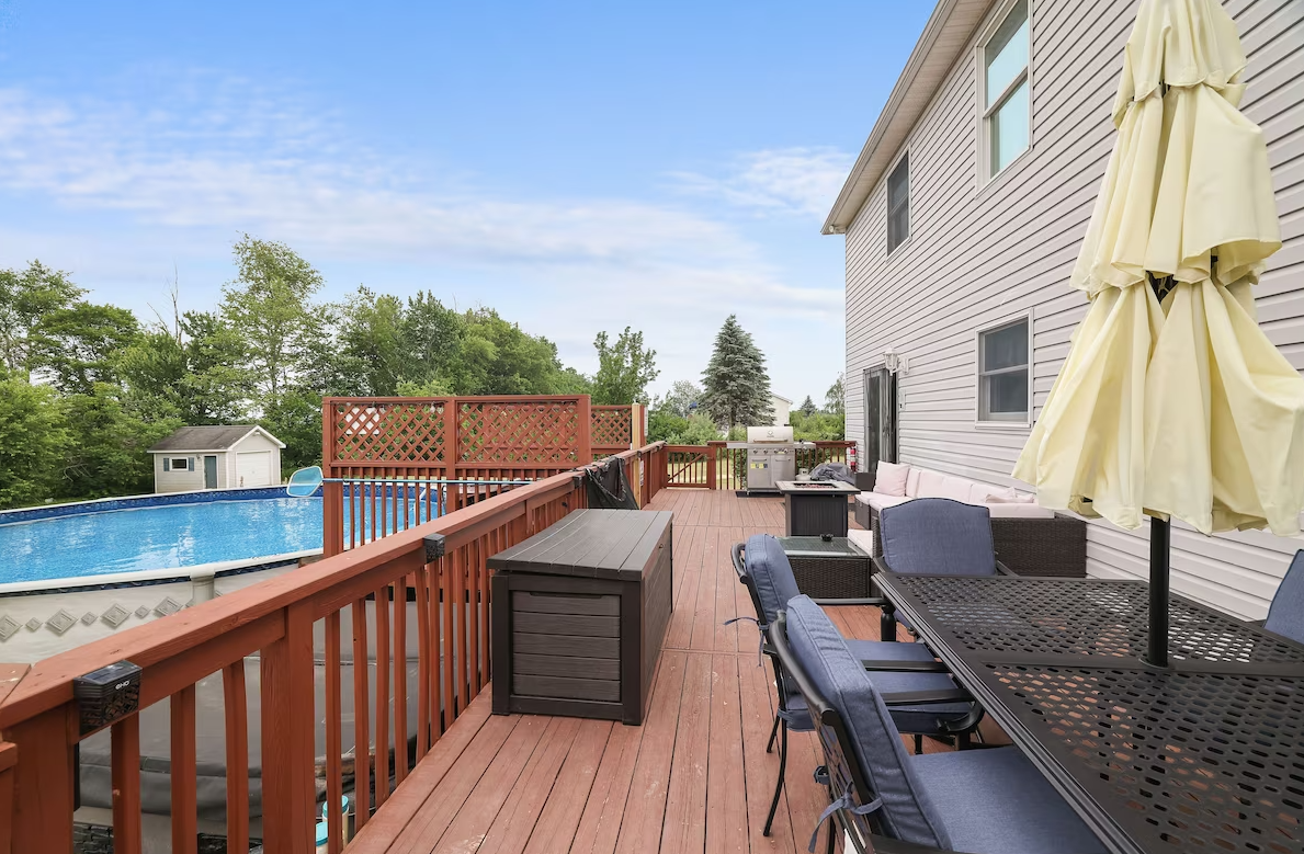 A large wooden deck with a table and chairs and an umbrella.