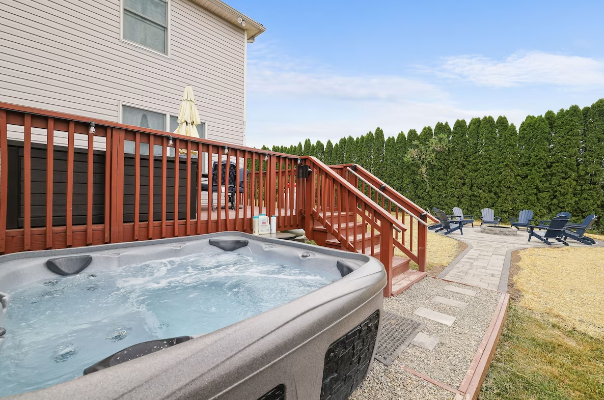A hot tub is sitting on a deck next to a house.