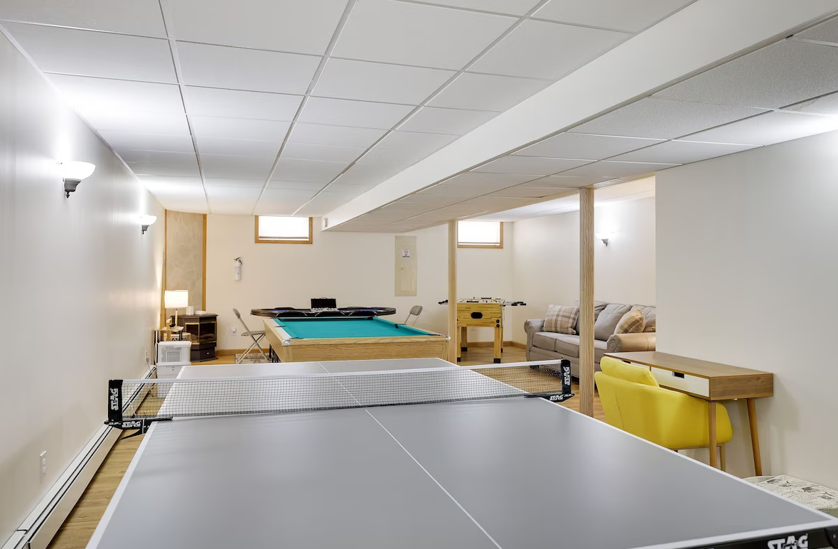 A basement with a pool table and a ping pong table