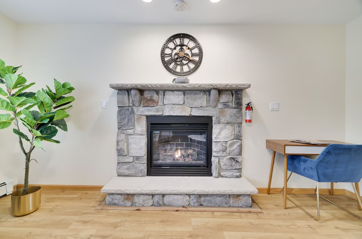 A living room with a fireplace and a clock on the wall.