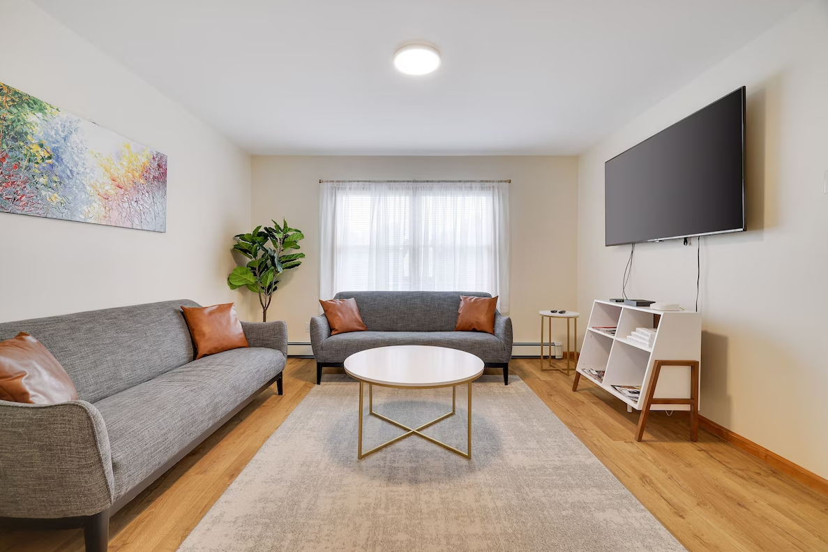 A living room with two couches , a coffee table , and a flat screen tv.