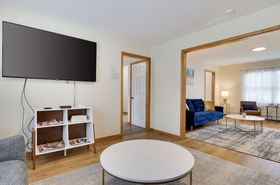 A living room with a flat screen tv and a round coffee table.
