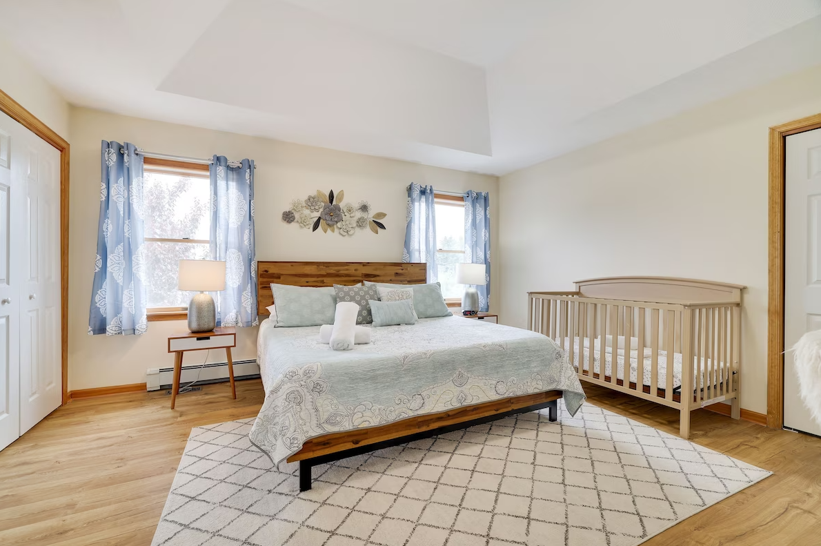 A bedroom with a king size bed and a crib.