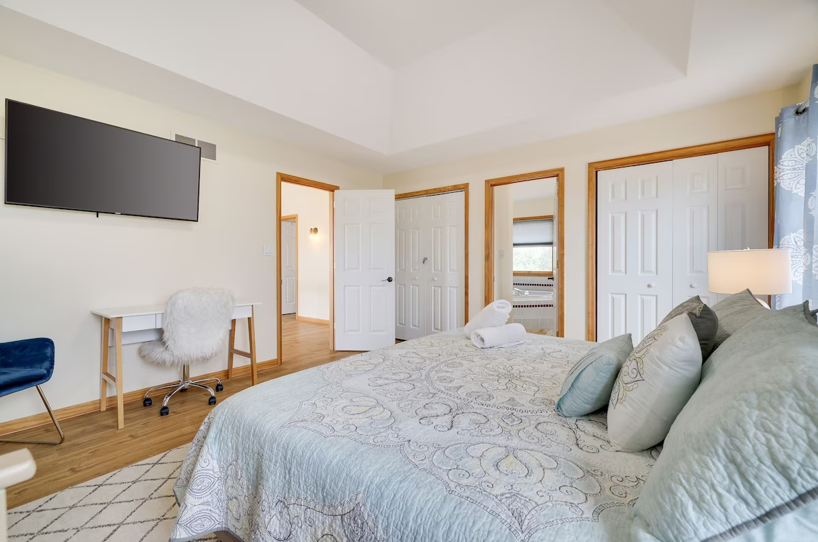 A bedroom with a large bed , desk and television.