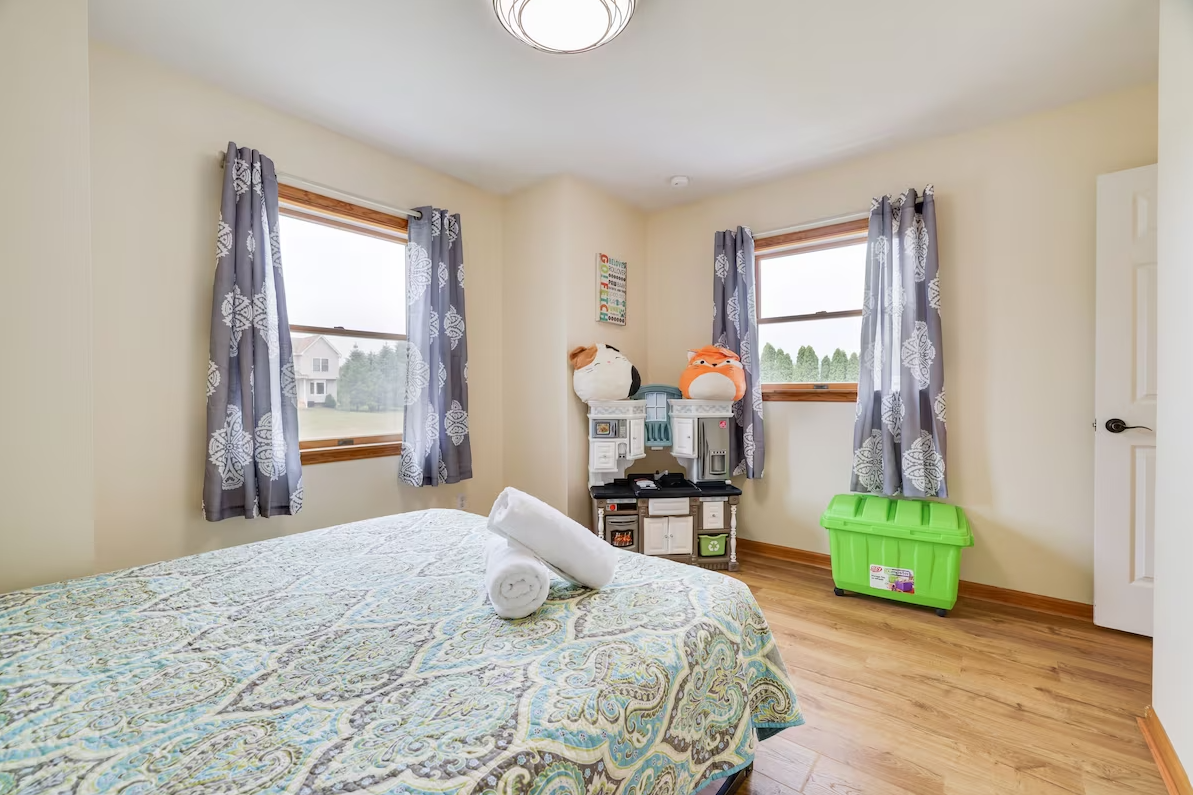 A bedroom with a bed , two windows and a green box.