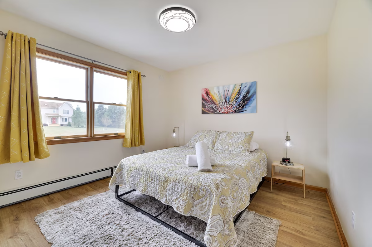 A bedroom with a king size bed , two windows and a rug.
