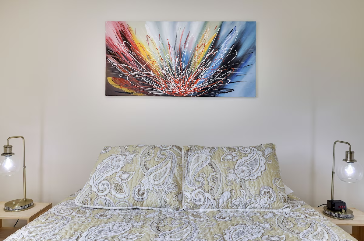There is a painting on the wall above the bed.