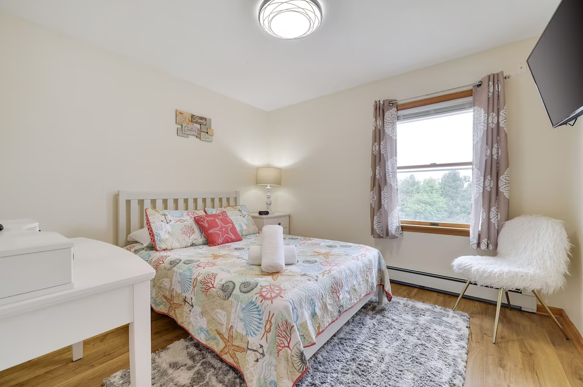 A bedroom with a bed , chair , table and television.